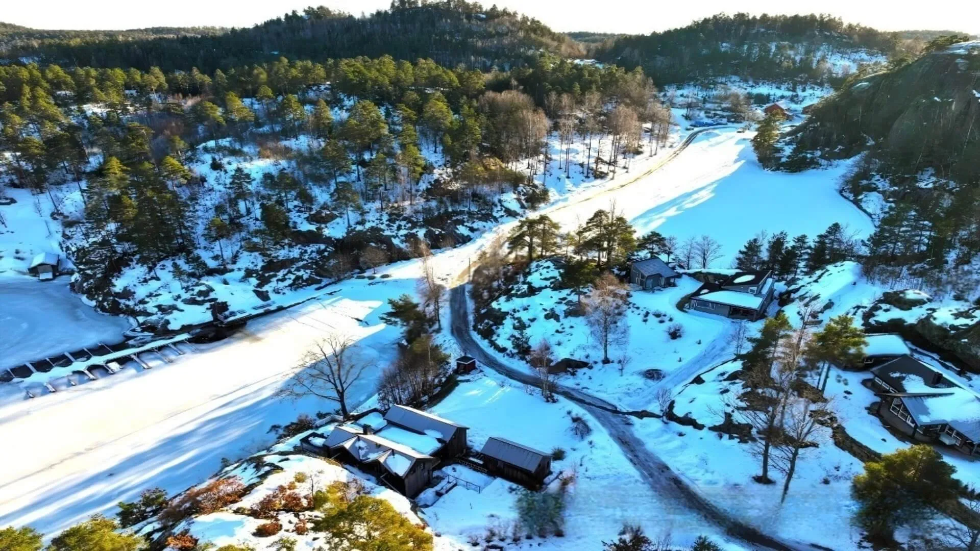 Luftfoto av hytteområde med vei og bebyggelse om vinteren